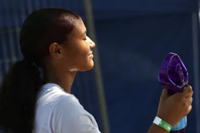 A woman sprays herself with a mister fan