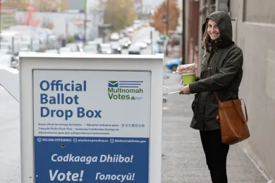 A person casting their ballot at a Mutlnomah County Elections Official Ballot Drop Box