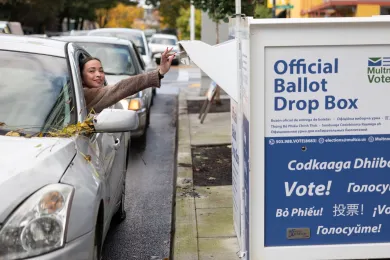 voter in vehicle drops off ballot at official ballot drop site