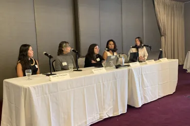 the four panelists and moderator seated at table during the panel discussion