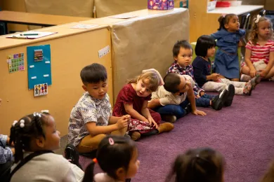 Preschoolers sit on the carpet at circle time