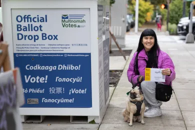 voter with pet holds ballot next to official ballot drop box