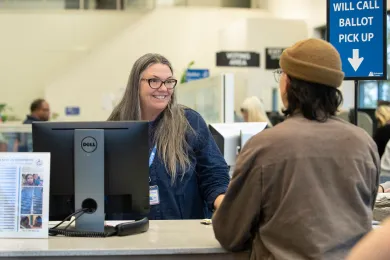 Election worker greets voter at will call counter with visible signage 