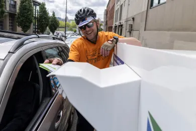 A bicyclist drops off their ballot at an Official Ballot Drop Site near the Multnomah County Elections Building. 