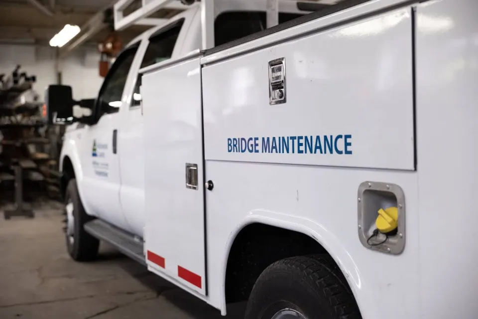 Side view of a white work truck labeled Bridge Maintenance.