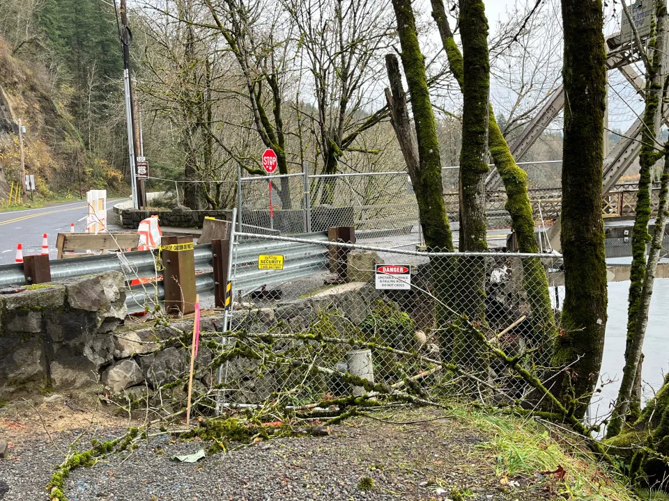A chain link fence blocks access to a retaining wall at one end of the Stark Street Bridge.
