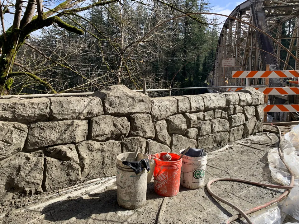 Work buckets and a hose next to the new shotcrete wall.