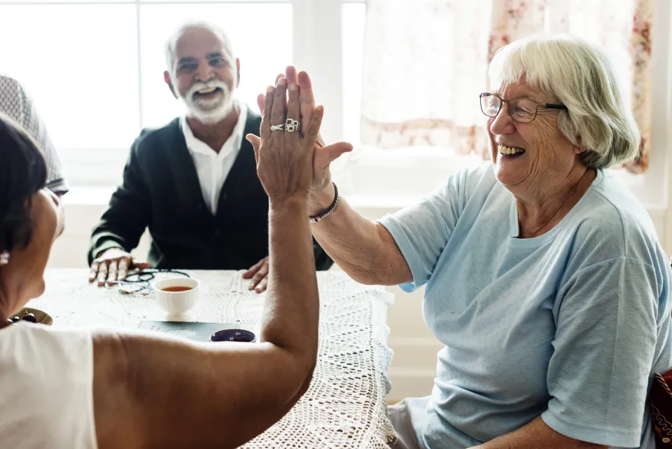 older adult smiles and high-fives another person