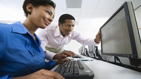 photo of woman at computer with man