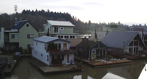 A moorage with several floating homes at wooden docks.