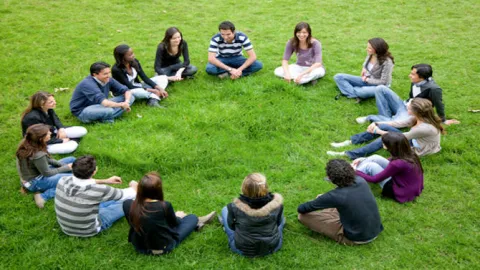 photo of youth sitting in circle on grass