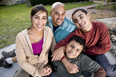 Latino family smiling outside.