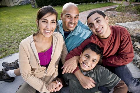 Latino family smiling outside. 