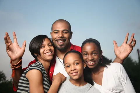 Father and three daughters smile at the viewer.