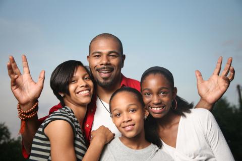 Father and three daughters smile at the viewer. 