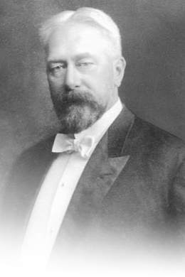 Black and white photo of a bearded man wearing white tie.