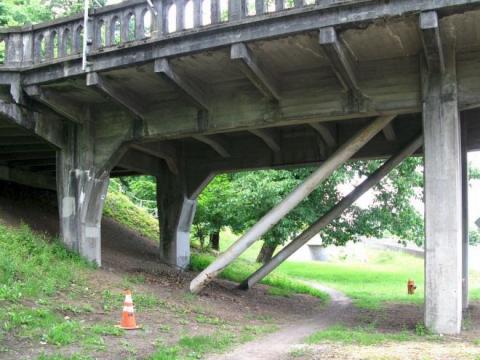 Wide steel bars running diagonally from the underside of the bridge to the ground.