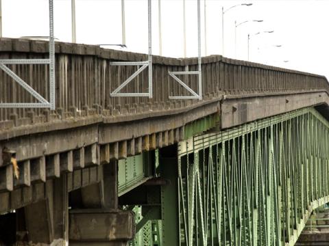 A side view of the bridge, showing uneven sections of concrete railing.