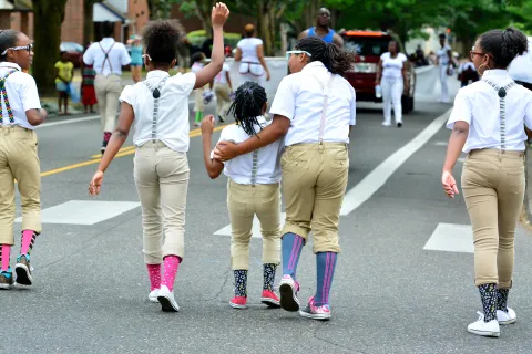Kids march in the 2015 Good in the Hood Parade, where people used fans, misters and hats to beat the heat.