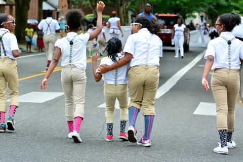 Kids march in the 2015 Good in the Hood Parade, where people used fans, misters and hats to beat the heat.