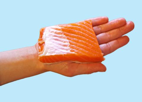 Child's hand holding a piece of raw fish