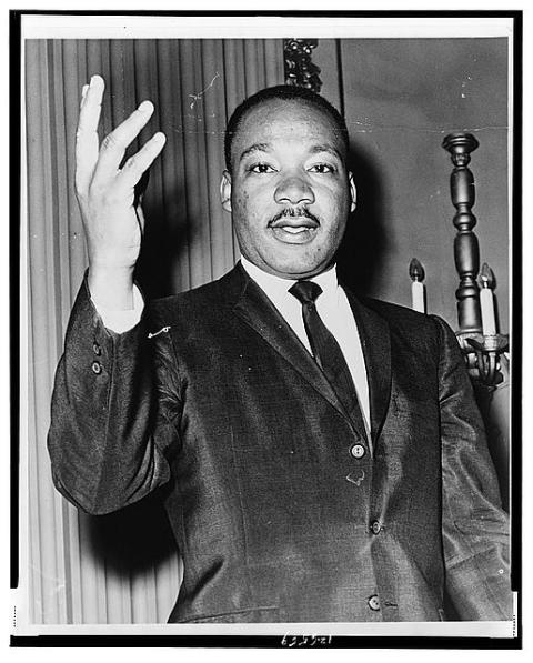 Dr. Martin Luther King, Jr. holds one hand up, mid speech