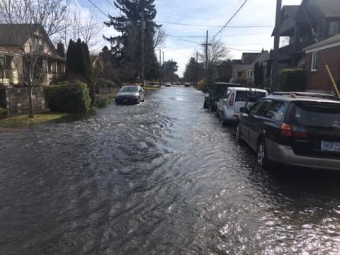 Water floods Northeast Portland streets after a water main break.