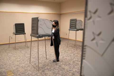 Voter wearing face covering votes in a voting booth at the Voting Center Express in Gresham