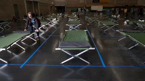 photo of someone setting up cots at the Oregon Convention Center social distancing shelter.