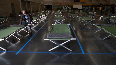 photo of someone setting up cots at the Oregon Convention Center social distancing shelter. 