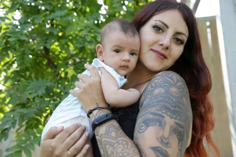 smiling, tattooed mother posing with infant