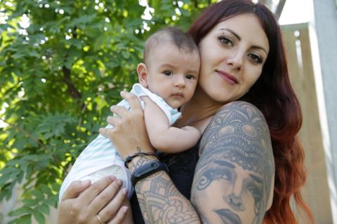 smiling, tattooed mother posing with infant 