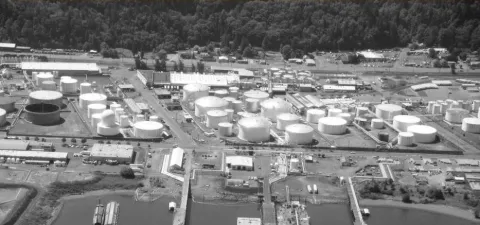 Large tanks for storing liquid fossil fuels adjacent to the Willamette River.