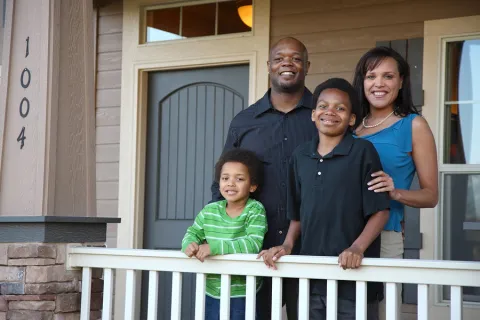 African American family smiling in front of their home