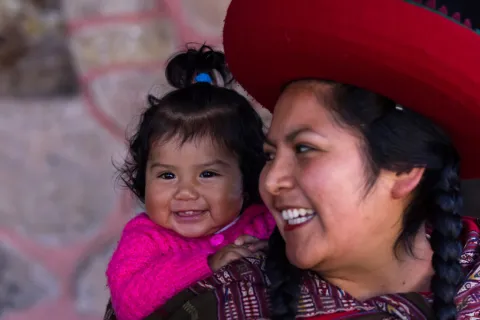 a child sleeping peacefully on the back of a smiling Latina mom