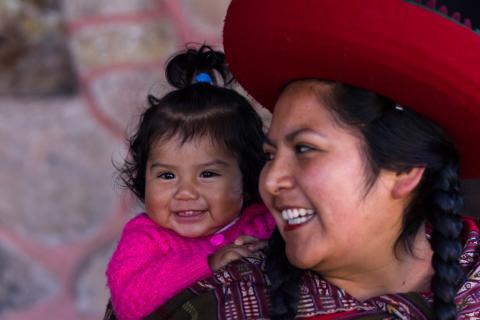 a child sleeping peacefully on the back of a smiling Latina mom