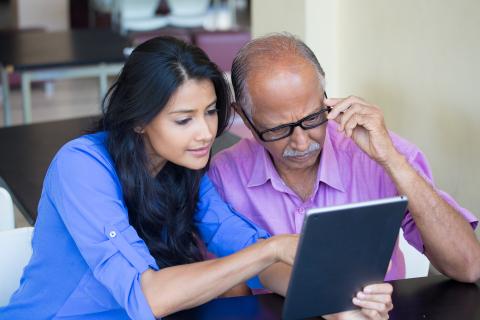 This is an image of a man looking at a tablet and a woman pointing at something on the tablet