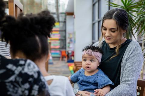 Mother holding her child on her lap talking with friend