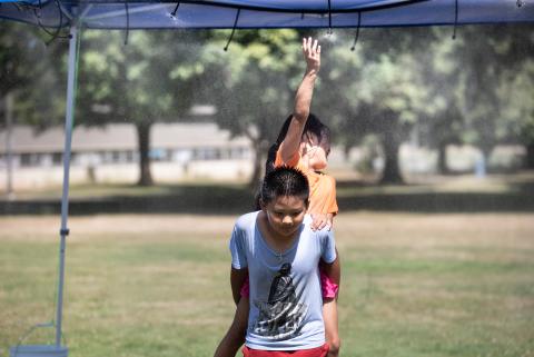 Kids play at a misting station in Knott Park, July 2021