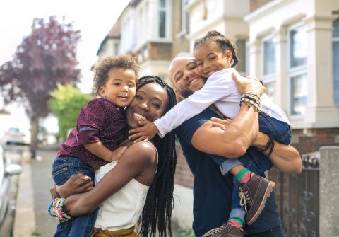 Family with two kids standing outside their home smiling