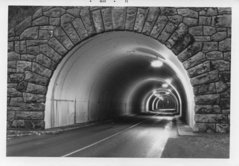 B/W photo looking into the Cornell Tunnel with some exterior brickwork and interior overhead lights visible.