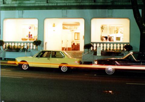 Exterior lobby view of the Martha Washington Hotel with a yellow and a black car parked in front.