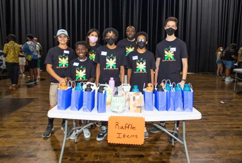 Youth advisory board members pose behind the raffle prize table at the youth summit.