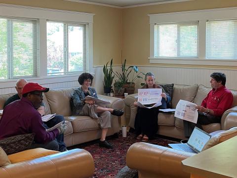 Council members reviewing and discussing documents in a living room.