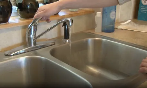 a kitchen faucet with water test sample bottles in the background