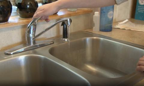 a kitchen faucet with water test sample bottles in the background