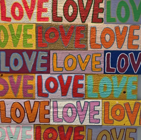 Bold and colorful painting shows the word "love" in a repeating pattern