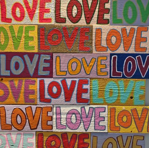 Bold and colorful painting shows the word "love" in a repeating pattern