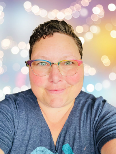 woman in grey and blue top with rainbow glasses