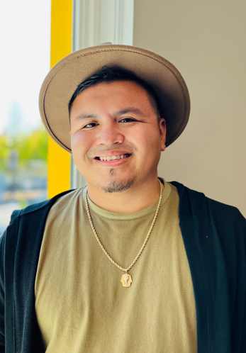 man in tan hat and top with gold necklace and black sweater